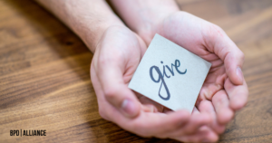 two hands holding a card on which "give" is written